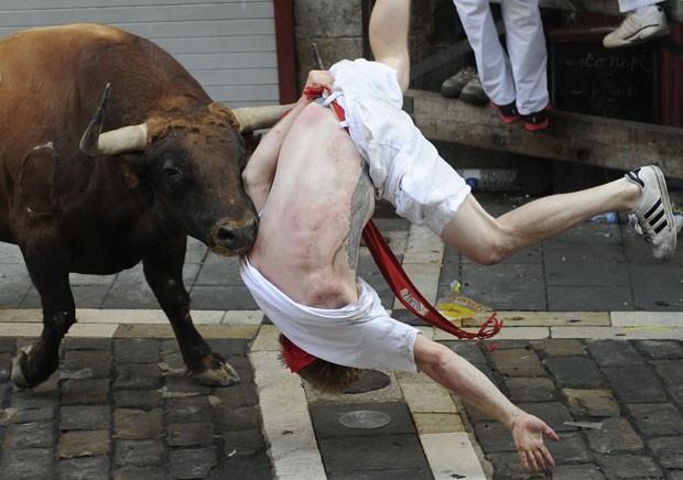 Touro ataca participante na primeira corrida do festival de Pamplona nesta terça-feira (7) (Foto: Ander Gillenea/AFP)