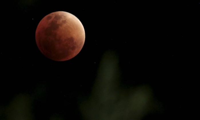 A lua, na cor vermelha escura, é coberta pela sombra da Terra durante eclipse lunar total em La Paz - DAVID MERCADO / REUTERS