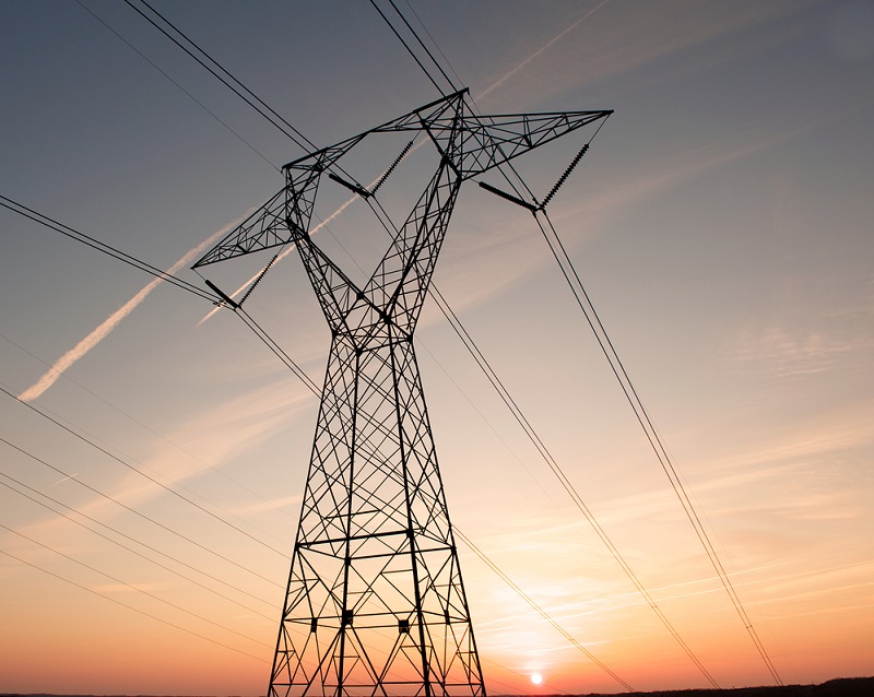 Electric power pylon and wires silhouetted by ab colorful sunset.
