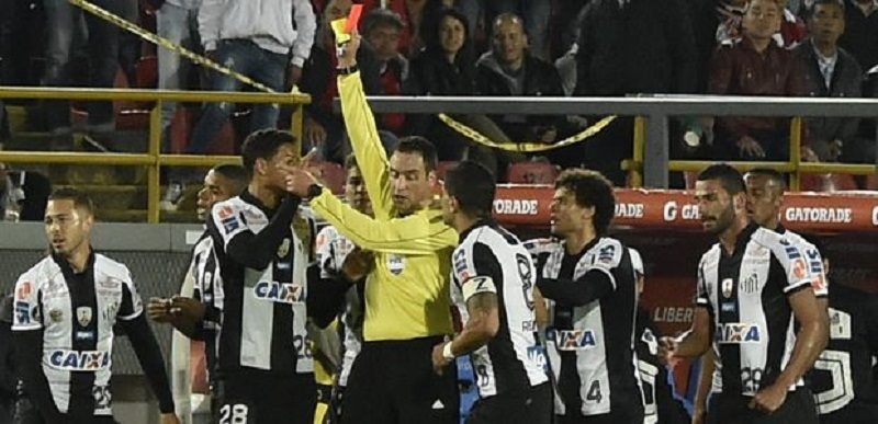 Referee Fernando Rapallini (C) of Argentina shows the red card to Brazil´s Santos player Jean Mota (L) during the Libertadores Cup football match against Brazil´s Santos at El Campin stadium in Bogota, Colombia on April 19, 2017. / AFP PHOTO / GUILLERMO MUNOZ ORG XMIT: 079