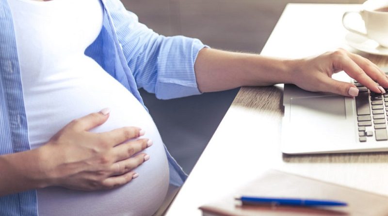 Cropped image of beautiful pregnant business woman using a laptop and holding one hand on her belly while working at home