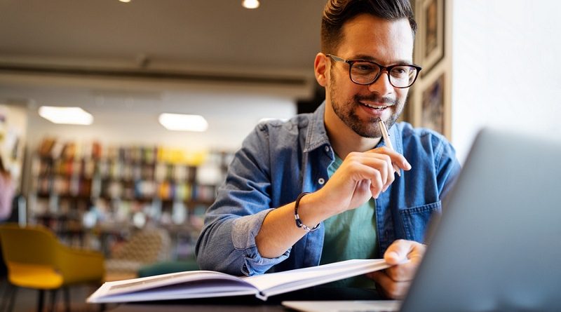 Smiling male student working and learning in a library