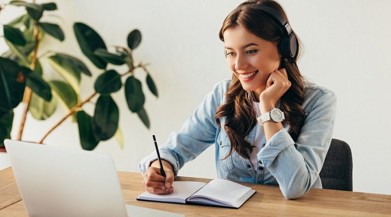 portrait of young smiling woman in headphones taking part in webinar in office