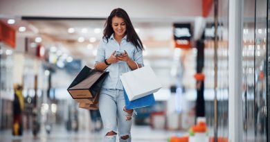 Brunette woman in the supermarket with many of packages and phone in hands have shopping day.