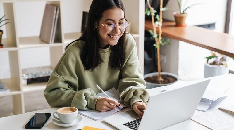Image of a pretty positive optimistic young girl student using laptop computer indoors studying.