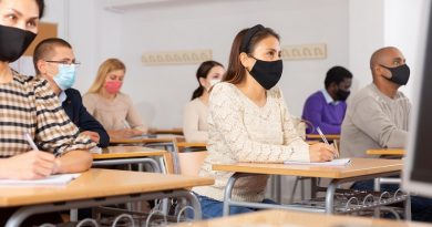 Young woman in protective face mask listening to lesson in extension school. Concept of necessary precautions and social distancing in coronavirus pandemic..