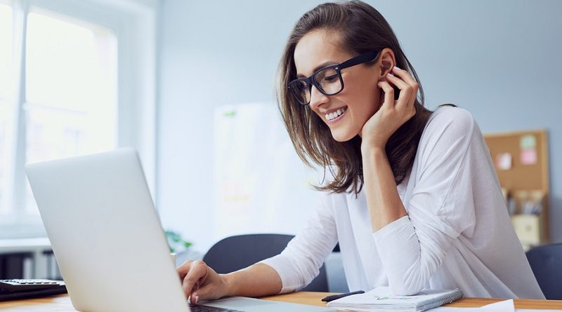 Portrait of veautiful cheerful young businesswoman working on laptop and laughing in home office