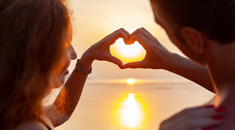 young sexu romantic couple in love happy on summer beach together having fun wearing swim suits showing heart sign on sundet