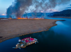 Uma pacata vila flutuante localizada nas plácidas margens do Lago Titicaca, situado na fronteira entre o Peru e a Bolívia, na Cordilheira dos Andes, em contraste com o perigo iminente de um incêndio florestal. — Foto: Yan Li (China)/World Photography Organisation