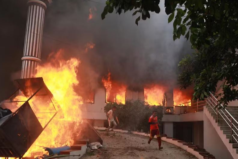 Manifestantes correm em meio a chamas no complexo do Parlamento nepalês durante um protesto em Catmandu, no Nepal, em 9 de setembro de 2025. — Foto: Prabin Ranabhat/AFP