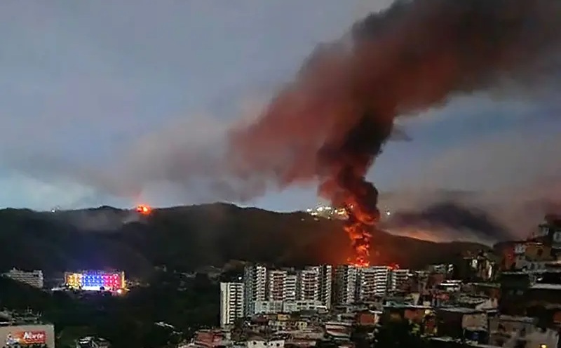 Um incêndio no Forte Tiuna, o maior complexo militar da Venezuela, é visto à distância após uma série de explosões em Caracas, em 3 de janeiro de 2026 (Foto:Gettey Imagens)